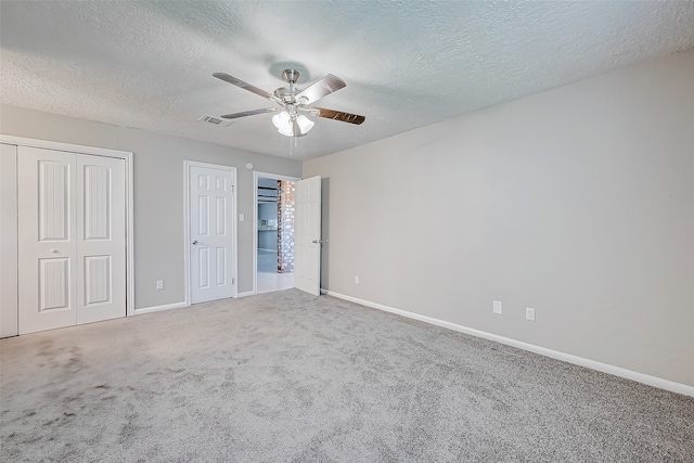 unfurnished bedroom featuring a textured ceiling, carpet floors, ceiling fan, and multiple closets