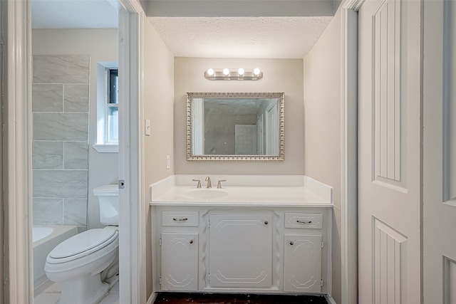 bathroom with a tub to relax in, vanity, a textured ceiling, and toilet