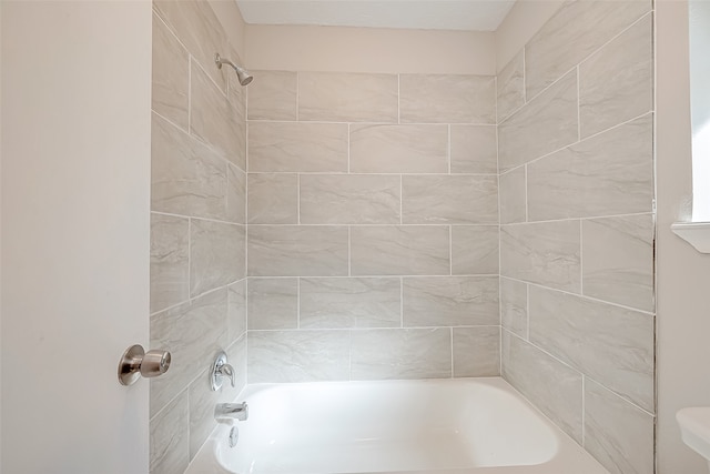 bathroom with tiled shower / bath combo and toilet