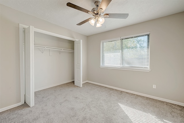 unfurnished bedroom featuring ceiling fan, light colored carpet, a textured ceiling, and a closet