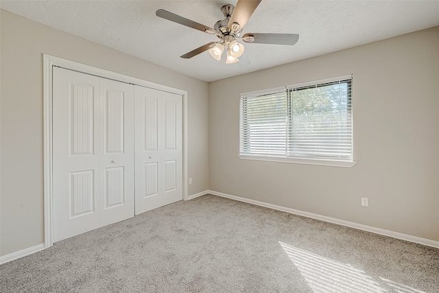 unfurnished bedroom with ceiling fan, light colored carpet, a textured ceiling, and a closet