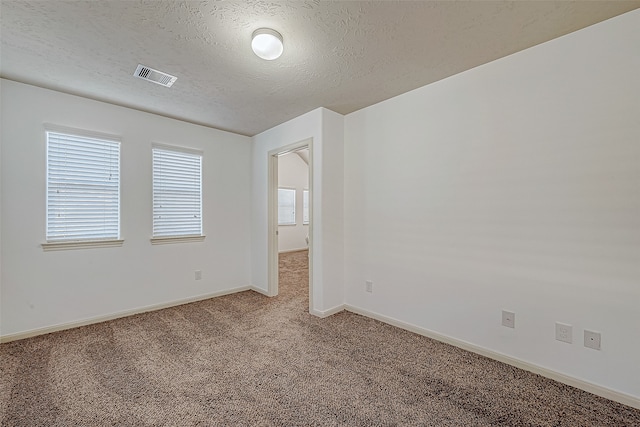 carpeted empty room featuring a textured ceiling