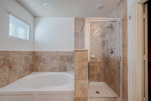 bathroom featuring a textured ceiling and shower with separate bathtub