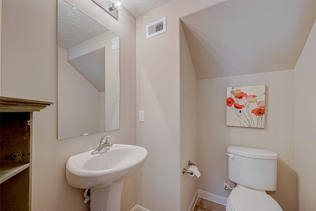 bathroom with vaulted ceiling, tile patterned flooring, a textured ceiling, and toilet