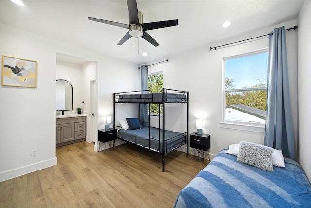 bedroom with ceiling fan, connected bathroom, and light hardwood / wood-style flooring