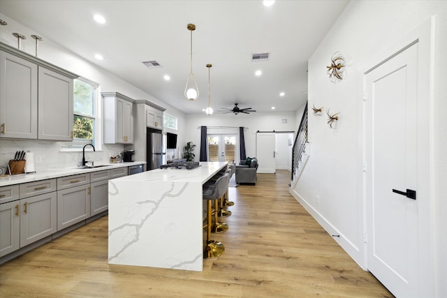 kitchen with decorative backsplash, a kitchen breakfast bar, ceiling fan, light hardwood / wood-style flooring, and a kitchen island