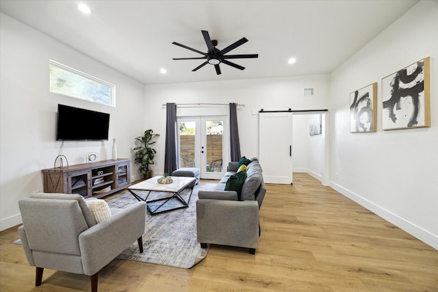 living room featuring french doors, a barn door, light hardwood / wood-style floors, and ceiling fan