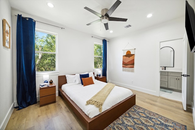 bedroom featuring light wood-type flooring, ceiling fan, and connected bathroom