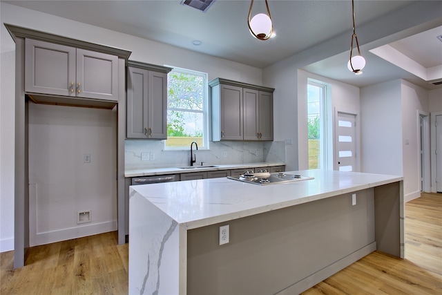 kitchen featuring tasteful backsplash, light hardwood / wood-style flooring, pendant lighting, and stainless steel gas cooktop