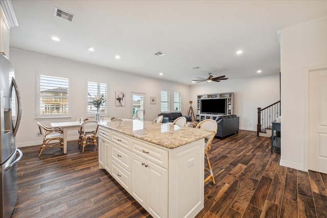 kitchen featuring stainless steel refrigerator with ice dispenser, dark hardwood / wood-style flooring, a kitchen island, and a breakfast bar area