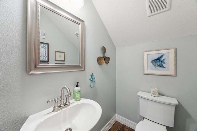 bathroom featuring hardwood / wood-style floors, toilet, lofted ceiling, and sink