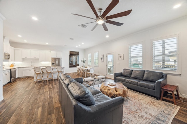 living room with dark hardwood / wood-style floors, ceiling fan, crown molding, and sink