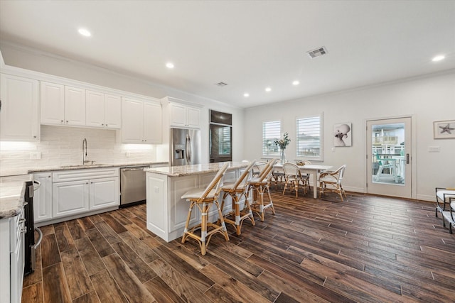 kitchen featuring white cabinetry, sink, dark wood-type flooring, stainless steel appliances, and a kitchen island