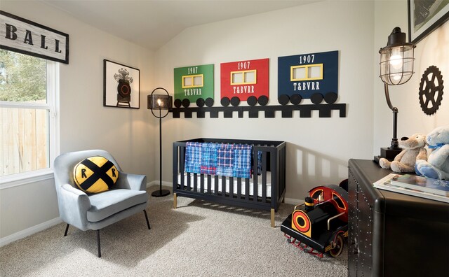 bedroom with lofted ceiling, a crib, and carpet floors