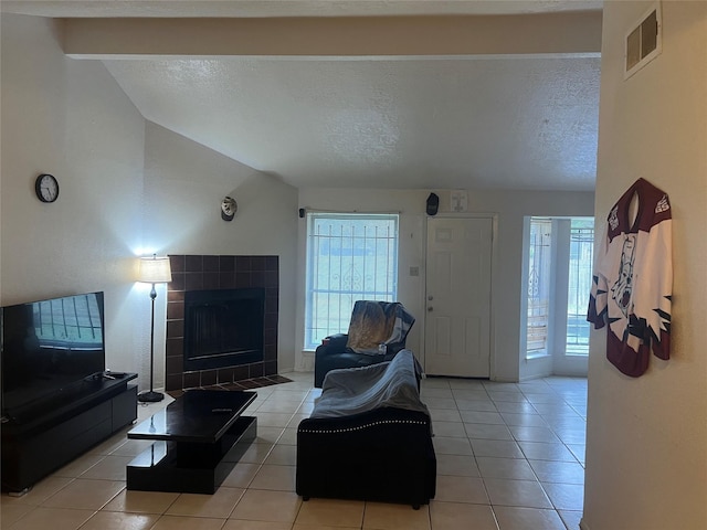 tiled living room with lofted ceiling with beams, a textured ceiling, and a tile fireplace