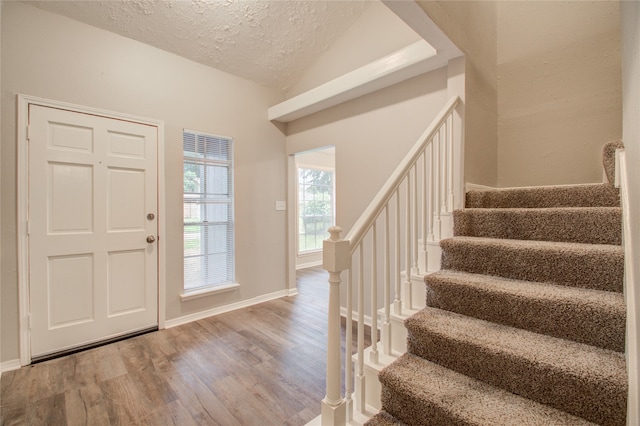 entryway featuring a textured ceiling, hardwood / wood-style flooring, and vaulted ceiling