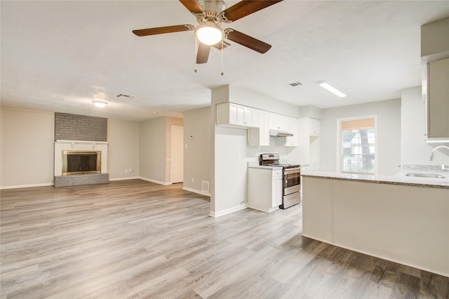 kitchen with white cabinets, light stone countertops, stainless steel range with electric cooktop, and light hardwood / wood-style flooring