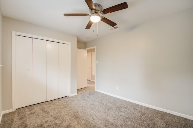 unfurnished bedroom with ceiling fan, light colored carpet, and a closet