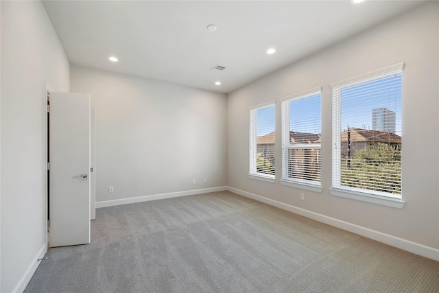 empty room with recessed lighting, light colored carpet, visible vents, and baseboards