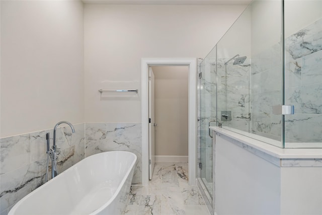 full bathroom featuring marble finish floor, a wainscoted wall, tile walls, a shower stall, and a freestanding tub