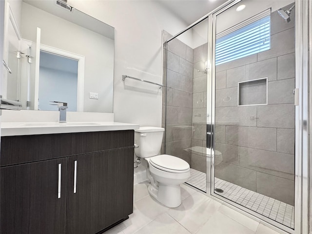 bathroom featuring toilet, vanity, tile patterned floors, and an enclosed shower