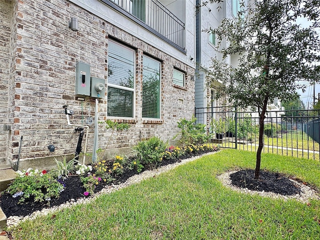 view of property exterior featuring a yard, brick siding, and fence