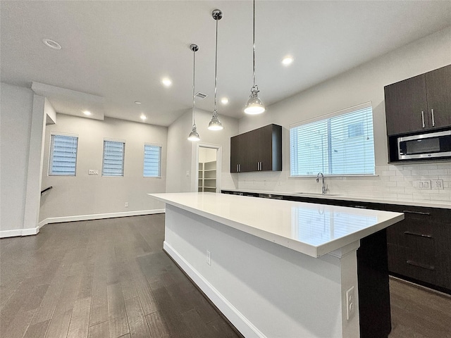 kitchen featuring dark brown cabinets, a kitchen island, dark wood-type flooring, and sink