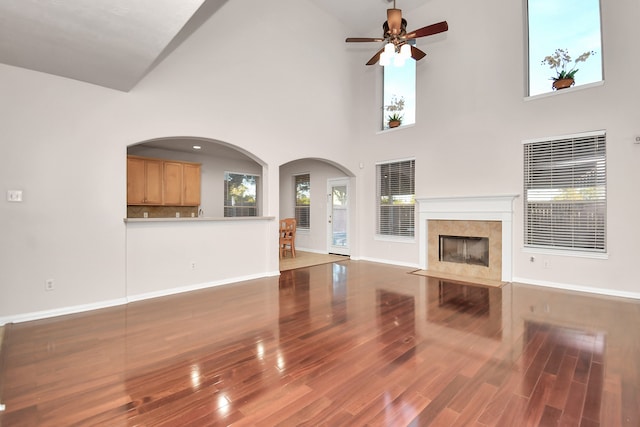 unfurnished living room with hardwood / wood-style floors, ceiling fan, and high vaulted ceiling