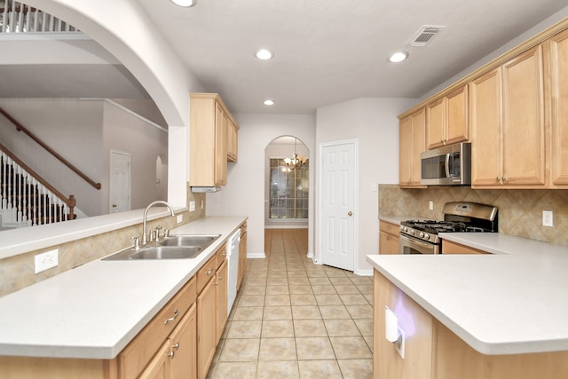 kitchen with light brown cabinets, backsplash, an inviting chandelier, sink, and stainless steel appliances