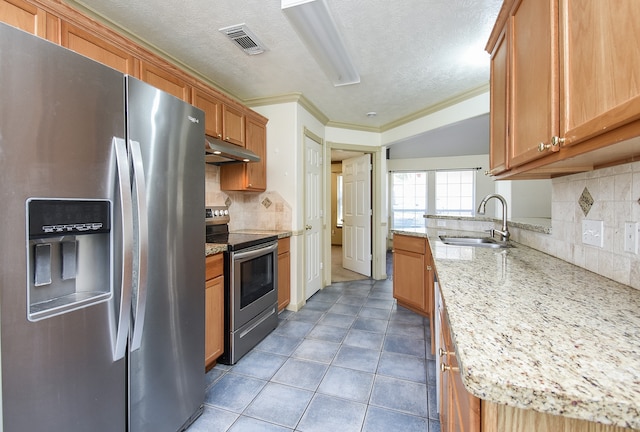 kitchen featuring backsplash, light stone counters, sink, and appliances with stainless steel finishes