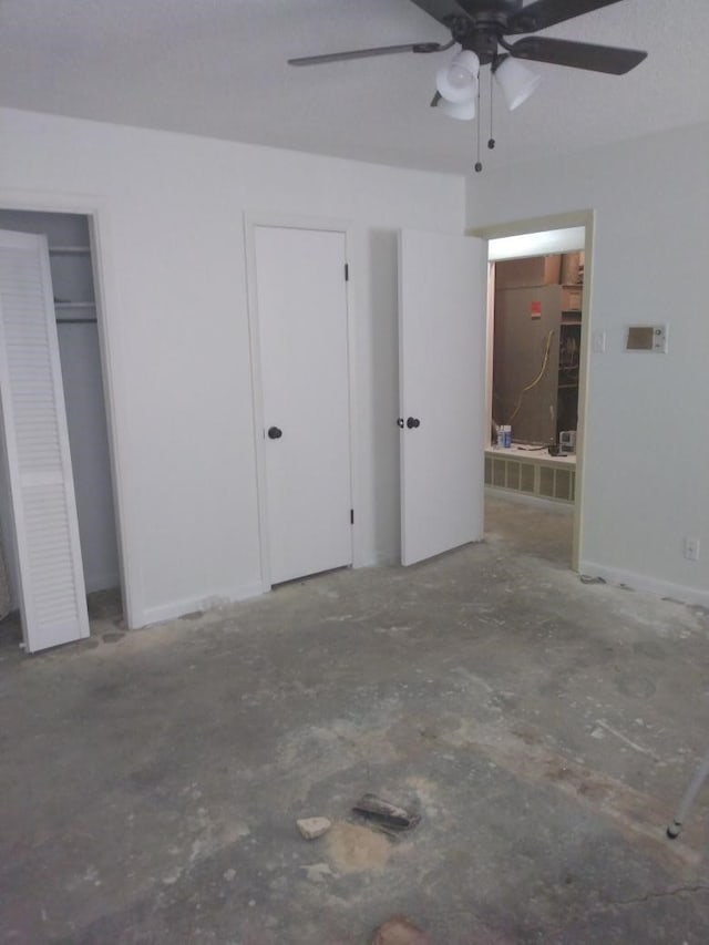 unfurnished bedroom with ceiling fan, ensuite bath, and two closets