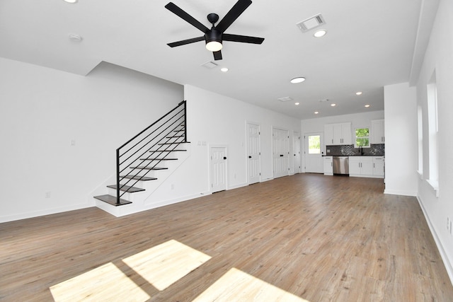 unfurnished living room with ceiling fan, sink, and light wood-type flooring