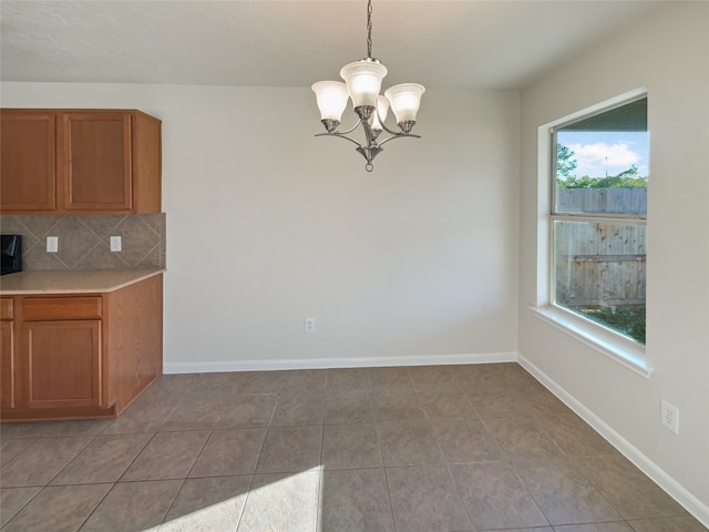 kitchen with decorative light fixtures, light tile patterned floors, backsplash, and a chandelier