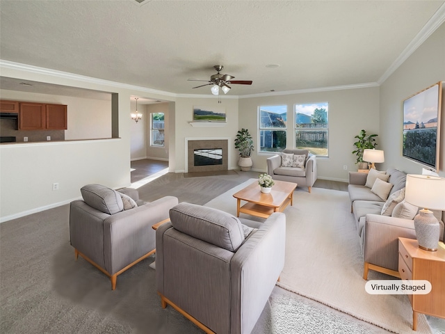 living room with ceiling fan with notable chandelier, dark carpet, and crown molding