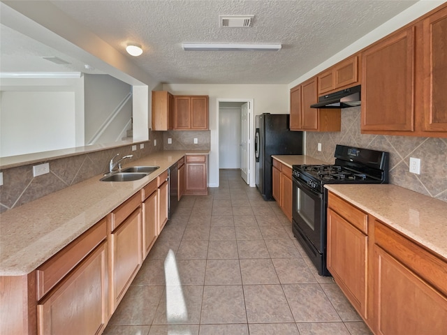 kitchen with sink, tasteful backsplash, light stone counters, light tile patterned floors, and black appliances