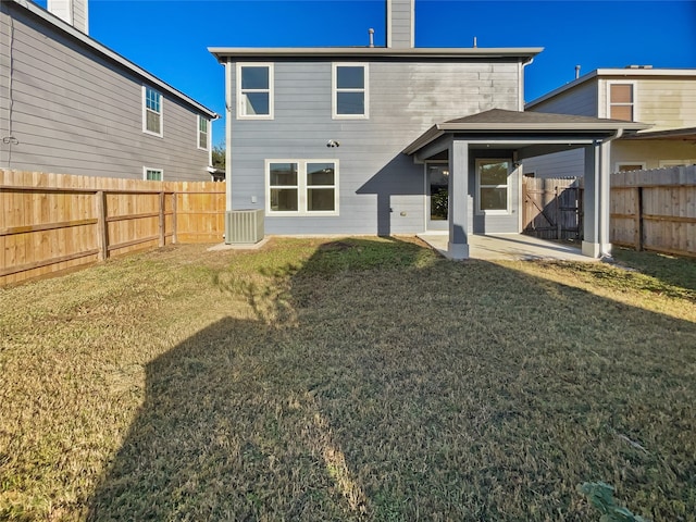 rear view of house with a lawn, central AC, and a patio