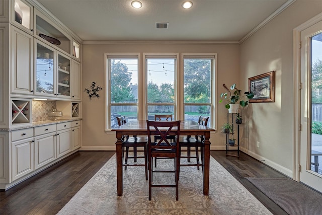 dining space with dark wood-style floors, ornamental molding, visible vents, and baseboards