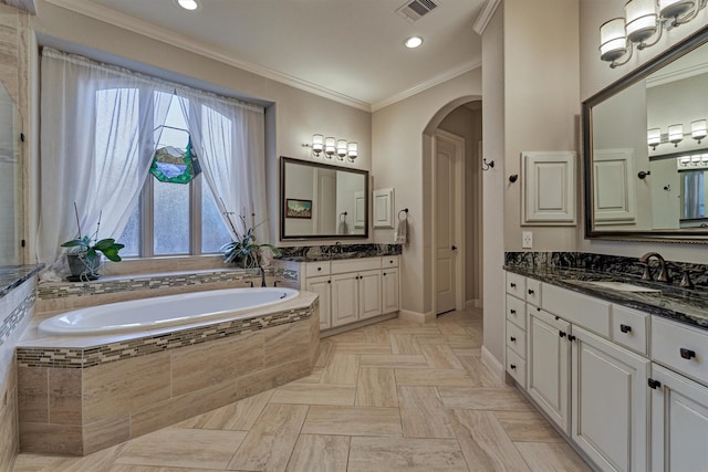 bathroom with visible vents, two vanities, a garden tub, crown molding, and a sink