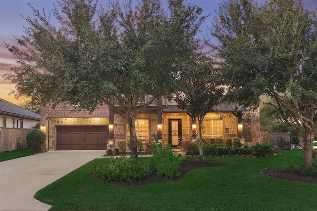 view of front of home featuring driveway, a garage, stone siding, fence, and a front yard