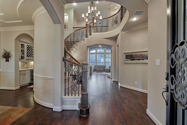 foyer entrance featuring wine cooler, an inviting chandelier, dark wood-type flooring, and ornamental molding