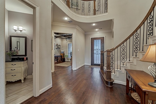 foyer entrance with a high ceiling, dark hardwood / wood-style floors, ceiling fan, and crown molding