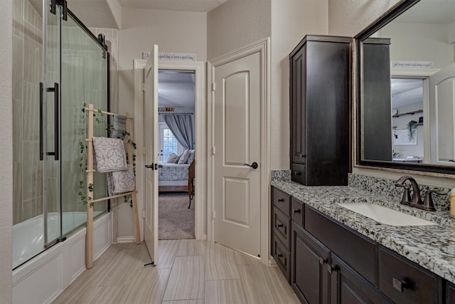 ensuite bathroom featuring enclosed tub / shower combo, a textured wall, vanity, and ensuite bathroom