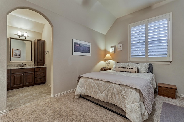 bedroom with ensuite bathroom, sink, light carpet, and lofted ceiling