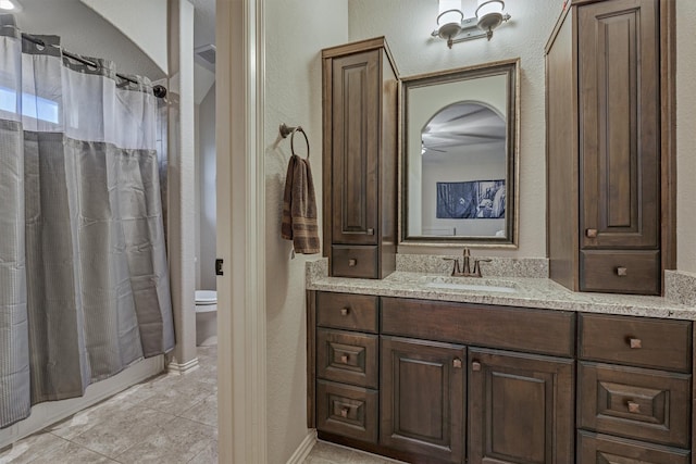 full bathroom with a textured wall, vanity, toilet, and tile patterned floors