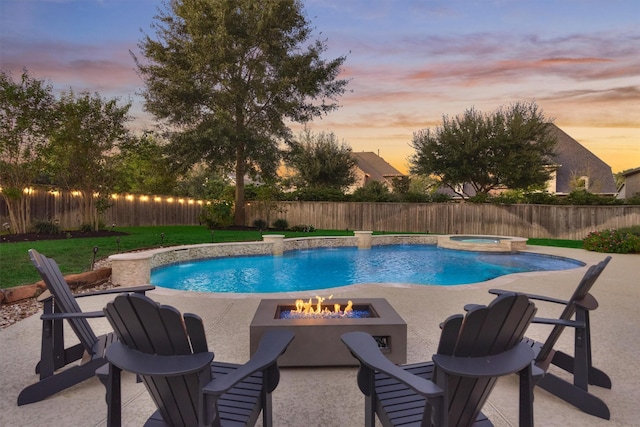 pool at dusk with a fenced backyard, a patio, a fenced in pool, and an in ground hot tub