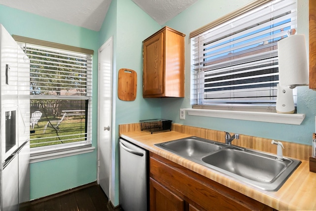 kitchen featuring dishwasher, a healthy amount of sunlight, a textured ceiling, and sink