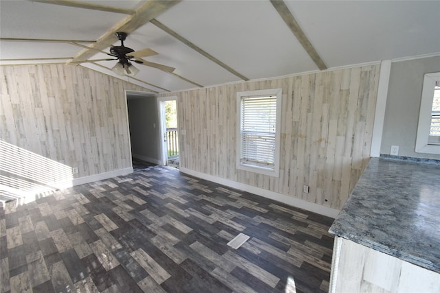 unfurnished living room featuring ceiling fan, lofted ceiling with beams, dark hardwood / wood-style floors, and wooden walls