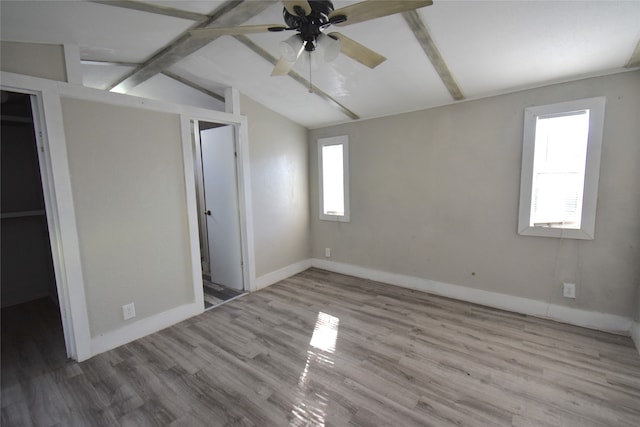 unfurnished bedroom with light hardwood / wood-style flooring, vaulted ceiling with beams, ceiling fan, a spacious closet, and a closet