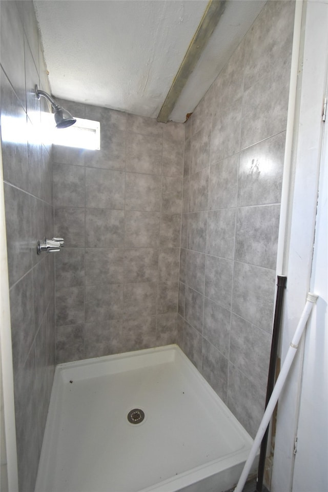 bathroom with a textured ceiling and tiled shower