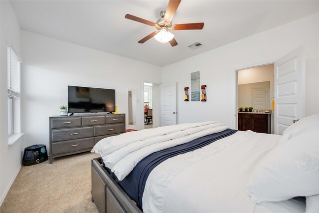 bedroom with connected bathroom, ceiling fan, and light colored carpet